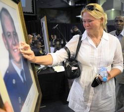 Die bedroefde Marelize Henning by 'n portret van haar man tydens die gedenkdiens wat vir al die slagoffers van die helikopterongeluk gehou is