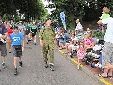 Hier stap Ds Fowles saam met 'n groep burgerlikes op die roete deur die strate van Nijmegen, terwyl duisende toeskouers toekyk