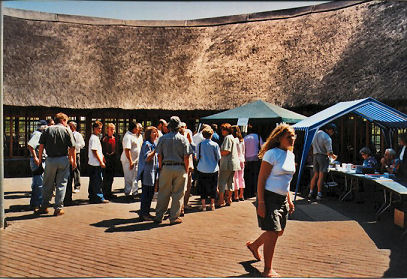 Feesgangers staan tou voor die registrasietafels.  Hier het die groot kennismaking en gesels reeds begin.