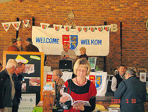 Die Henning stalletjie by die Genealogie- en Erfenisfees. In die agtergrond is van die bestuurslede besig om met besoekers te gesels. In die voorgrond is Sylvia Grobler (gebore Henning) besig om deur 'n boek op uitstalling te blaai